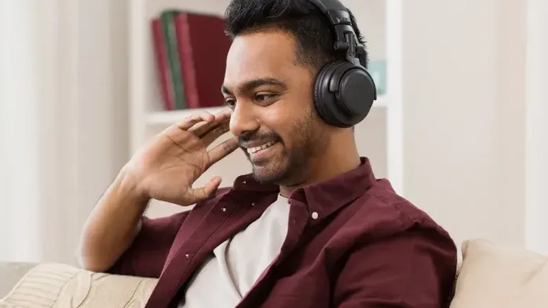 An adult learner smiling during an online lesson with headphones on